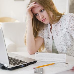 做贷款文书工作的少妇在与膝上型计算机的桌上“width=