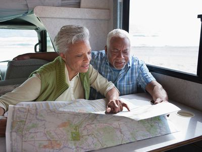 一对退休夫妇在房车里看地图，规划他们的路线。