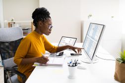 妇女在桌面电脑上用打开的活页夹处理税务