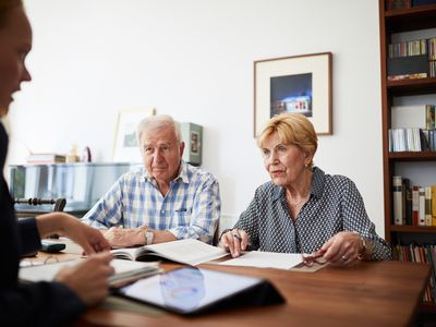 一对老夫妇与一位信用顾问会面，讨论他们的债务减免方案。＂width=