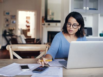 女人坐在笔记本电脑前使用计算器在线支付账单