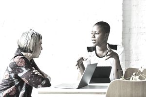 一个坐在平板电脑上的女人认真地和一个面前放着笔记本电脑的女人说话