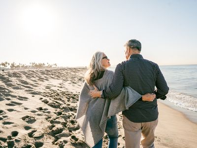 一对幸福的退休夫妇在海滩上散步。