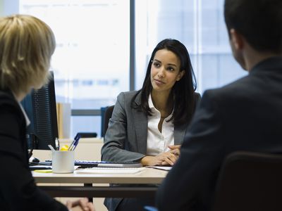 女企业主管坐在办公桌上讲话与两个同事讲话