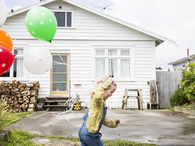 一个孩子在房子前跑步时握着气球