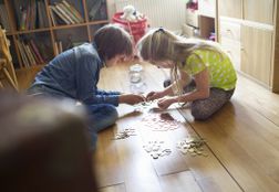 两个孩子一起在地板上计算硬币“width=