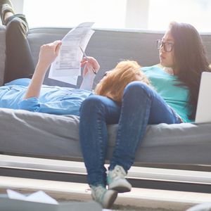 集中年轻夫妇检查税务文件而放松在家里沙发上”width=