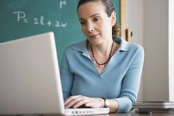 老师坐在黑板前，拿着数学方程，用笔记本电脑检查她的教学学位的税收优惠