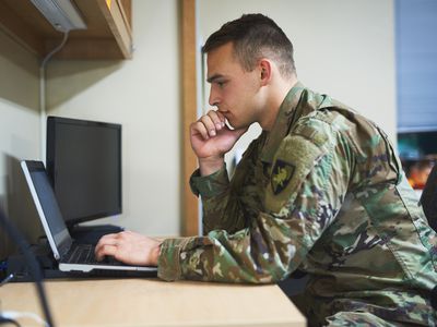 年轻的士兵在军事学院的宿舍中使用笔记本电脑