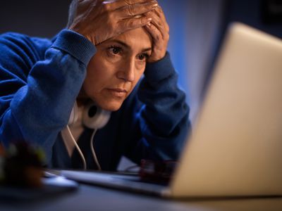 一名女子双手托着额头，惊恐地盯着笔记本电脑屏幕:她的僵尸债又来了＂width=