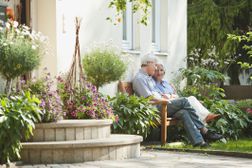 一对老夫妇坐在花园的房子外面。”width=