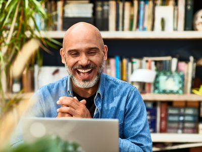 一个男人在笔记本电脑屏幕上显示的图像上开心。