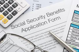 社会保障福利申请表，附笔、眼镜、计算器和文件。