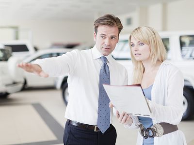 汽车推销员向客户展示汽车和审查付款计划。