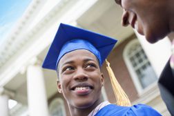 大学毕业生在蓝色帽子和褂子微笑在父母