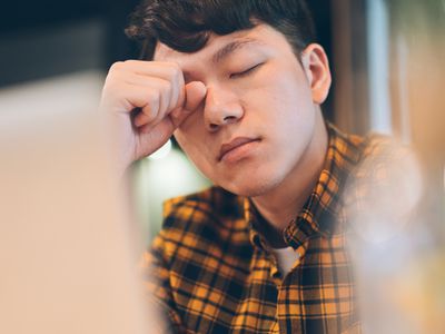 疲惫的年轻人在计算机前面摩擦眼睛。