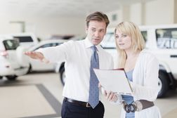 汽车推销员显示汽车和评论与客户付款计划。”width=