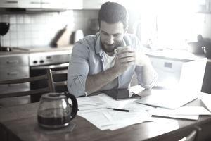 一名男子在厨房桌子边喝咖啡，咨询财务文件