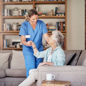 老年妇女与女性家庭保健助手一起经历长期护理保险的好处“width=