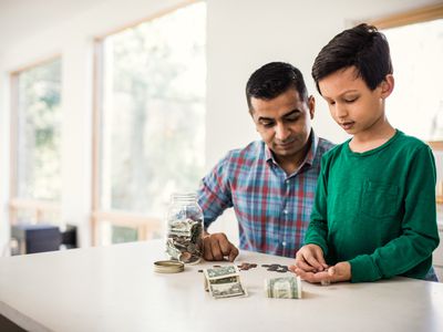 父亲和小儿子在家中计算美国的账单和硬币