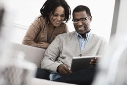 一对夫妻，一男一女坐着共用一台平板电脑。