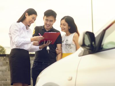 亚洲夫妇在经销商处购买和签署汽车销售合同
