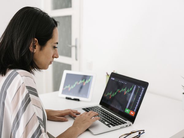 年轻的女交易员在家里用笔记本电脑阅读金融股票市场分析