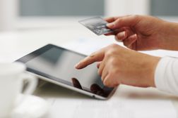 一个人在平板电脑上输入信用卡号码在线购物。