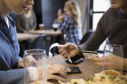 特写夫妇在啤酒厂餐厅用信用卡付账用智能手机计算小费