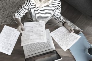 一名携带文件的妇女在家里使用笔记本电脑