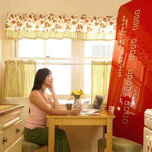 一个女人看着她的厨房里的巨额信用卡“width=