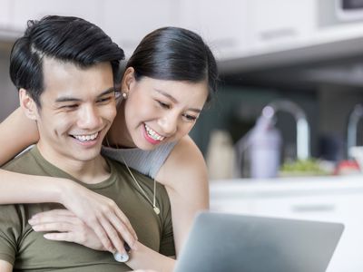一对年轻夫妇微笑着一起看着电脑屏幕＂width=