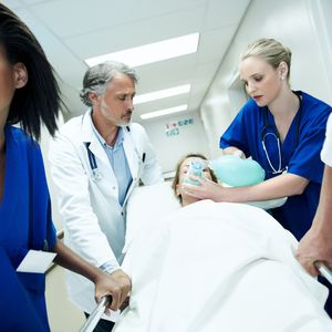 医生和护士把病人放在担架上推过急诊室，脸上戴着氧气面罩
