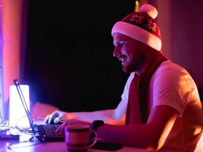 穿圣诞老人帽子的愉快的人在膝上型计算机贸易