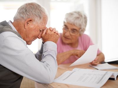 陷入困境的退休夫妇看着文件,皱眉