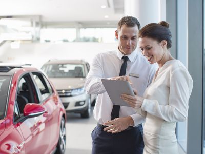 一个男人和一个女人在汽车经销商处审查一份文件。