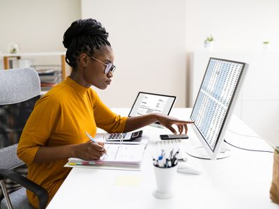 妇女在有开放活页夹的桌面计算机上工作税