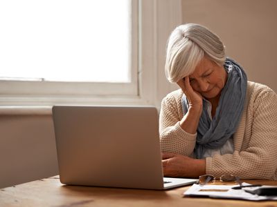 看起来膝上型计算机的年长妇女沮丧，当审查财务文件时