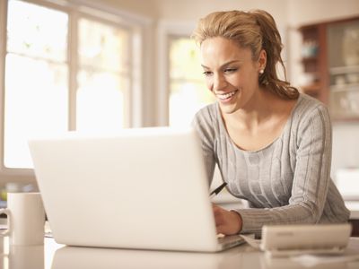 厨房里的女人在笔记本电脑上打字时微笑