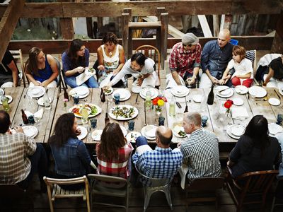 一群人聚集在他们公共生活区的餐桌上共享一顿饭＂width=