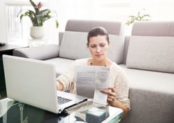 一个妇女坐在膝上型计算机前面的地板上，看文件“width=