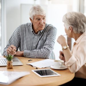 老年夫妇在餐桌上谈论财务问题“width=