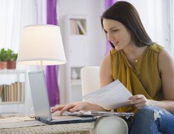 妇女在家在线养税在一台膝上型计算机“width=