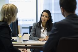 女性执行谈话与商业伙伴关于选择银行的。“width=
