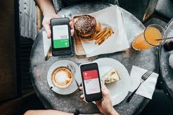 在餐厅用餐时，朋友们通过智能手机上的数字钱包设备发送/接收餐费的俯视图