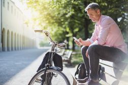 一个男人与一辆自行车在外面放松。”width=