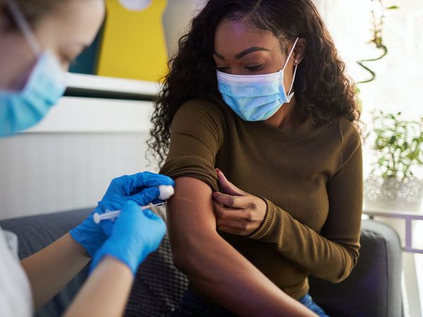 袖子卷起的女人从护士那里接种疫苗