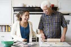 一个年长的男人和一个笑着的中年妇女站在厨房的柜台后面。