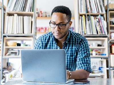 戴眼镜，穿着蓝色法兰绒衬衫的人在笔记本电脑上工作