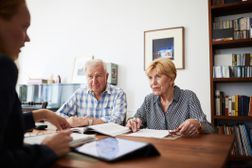 一对老夫妇会见信贷顾问审查他们的债务减免选项。”width=